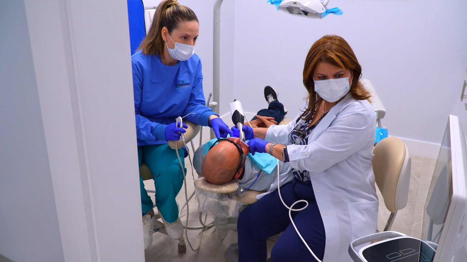 Advanced Digital Dental Technology for Precise Patient Care A dentist using a high-tech intraoral scanner on a patient in a modern dental office, assisted by a dental professional.